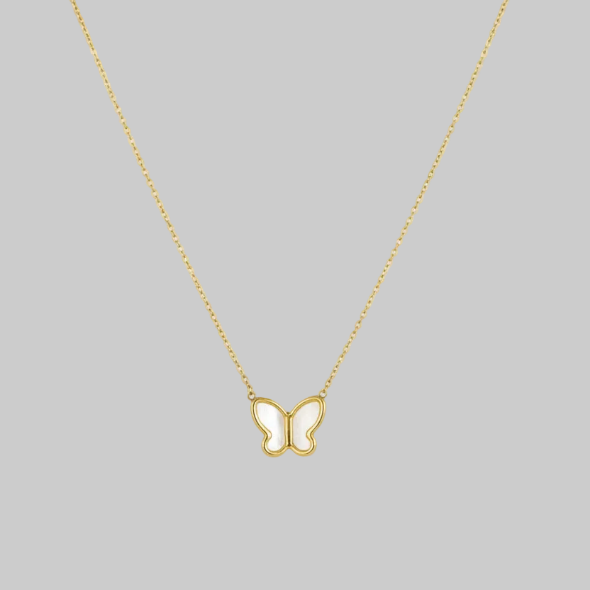 Gold butterfly necklace on a pink fabric background